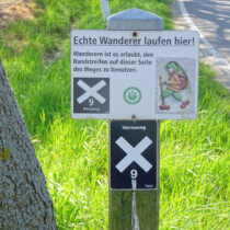 immer links am Straßenrand Schild Echte Wanderer laufen hier